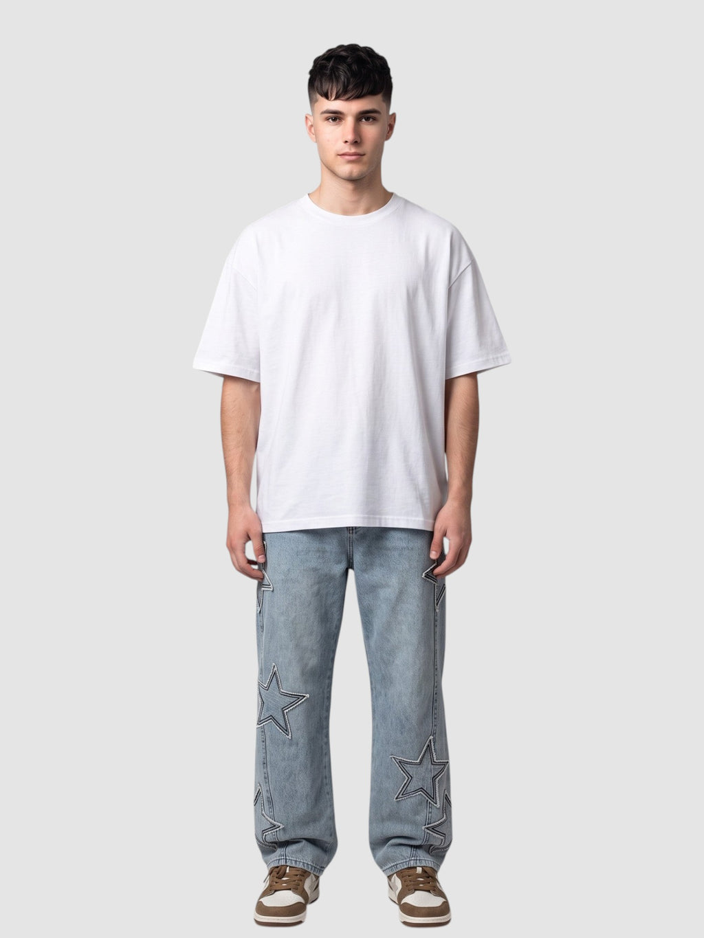 Y2K STUDIO light blue denim jeans with raw-edge star appliqués worn by a man with a white t-shirt and sneakers.