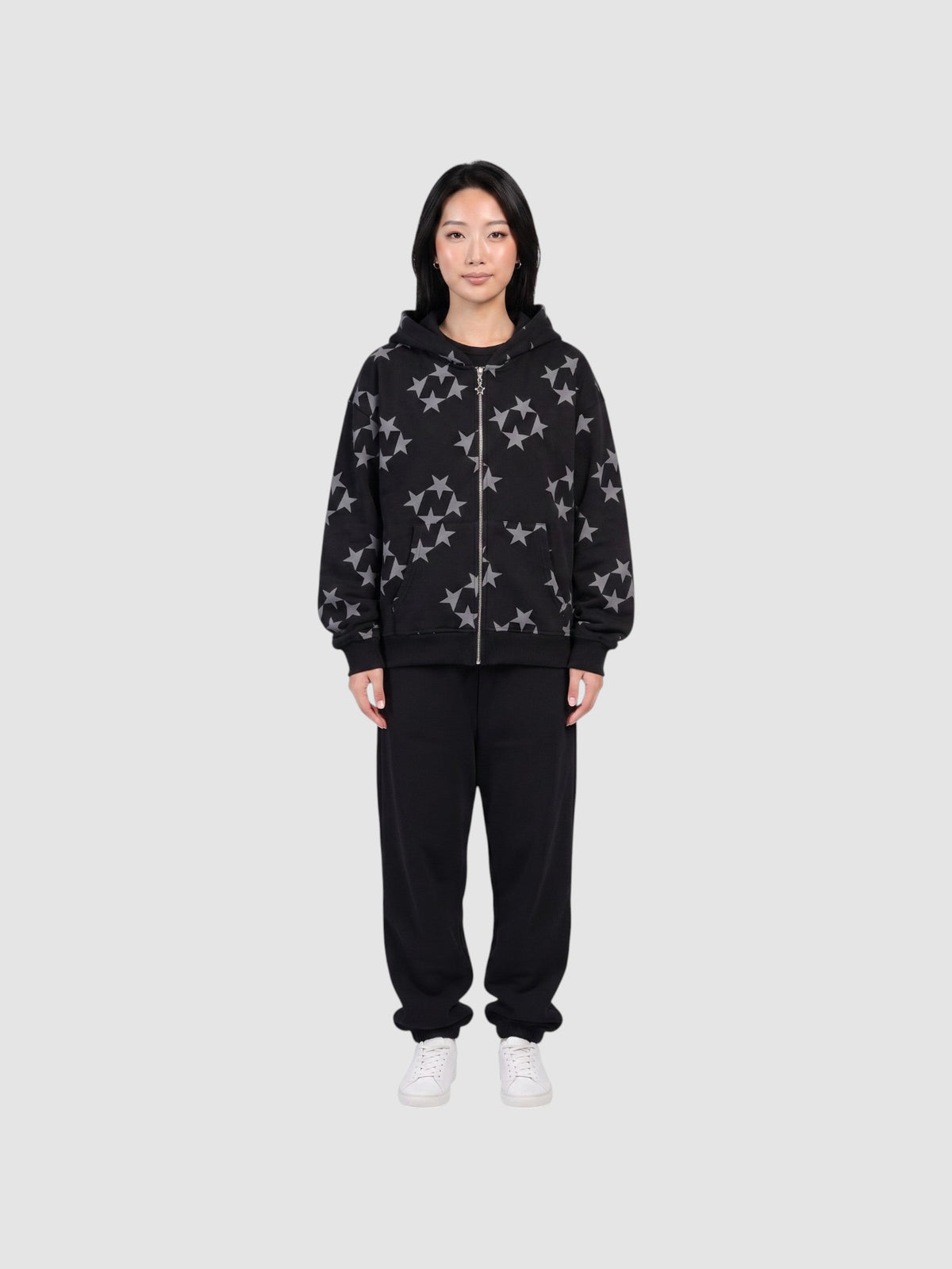 Model wearing a Y2K Studio black zip-up hoodie with a grey all-over star print, paired with black sweatpants.