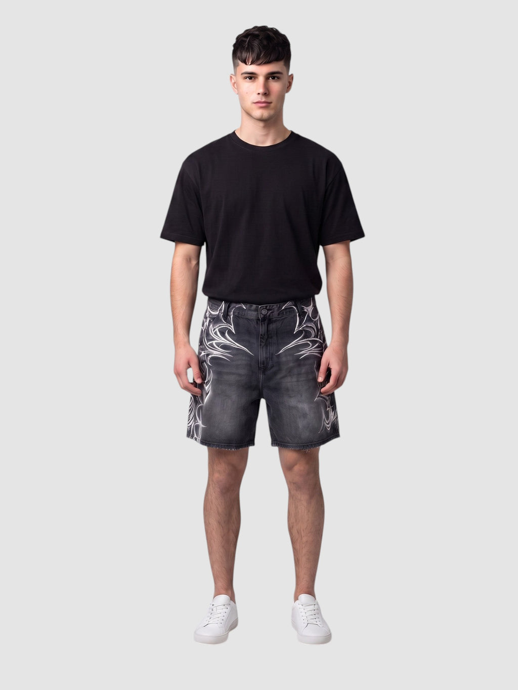 Y2K Studio black denim jorts featuring white airbrushed tribal motifs, raw hem, and loose fit on a male model.