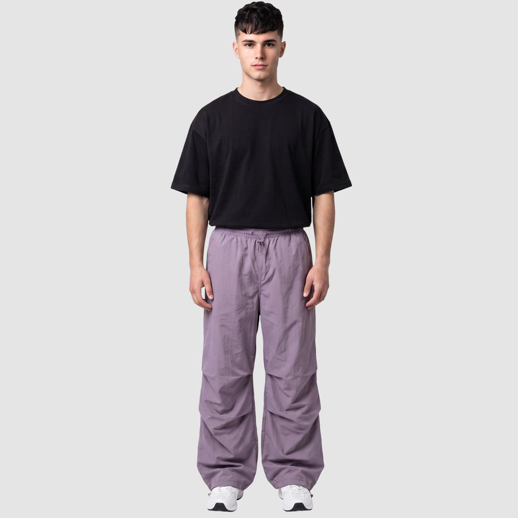 Y2K STUDIO model wearing a high-waisted matte violet parachute pant with gathered knees and adjustable drawstrings.
