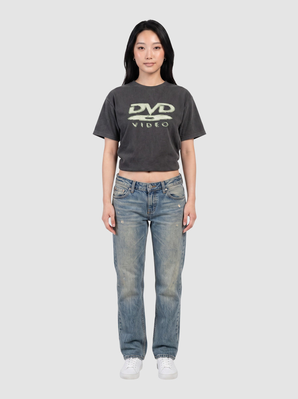 Y2K Studio black washed DVD Video graphic t-shirt worn by a model with blue jeans and white sneakers
