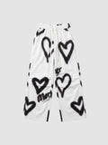 Y2K Studio white wide-leg pants featuring black spray-painted heart motifs and an elastic drawstring waist.