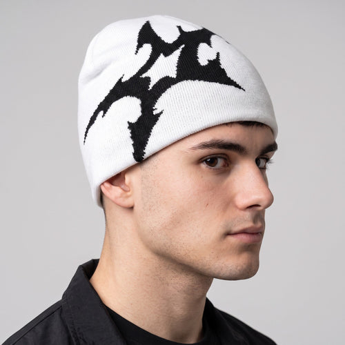 Y2K STUDIO white acrylic knit beanie featuring a bold black tribal-inspired graphic print on a male model
