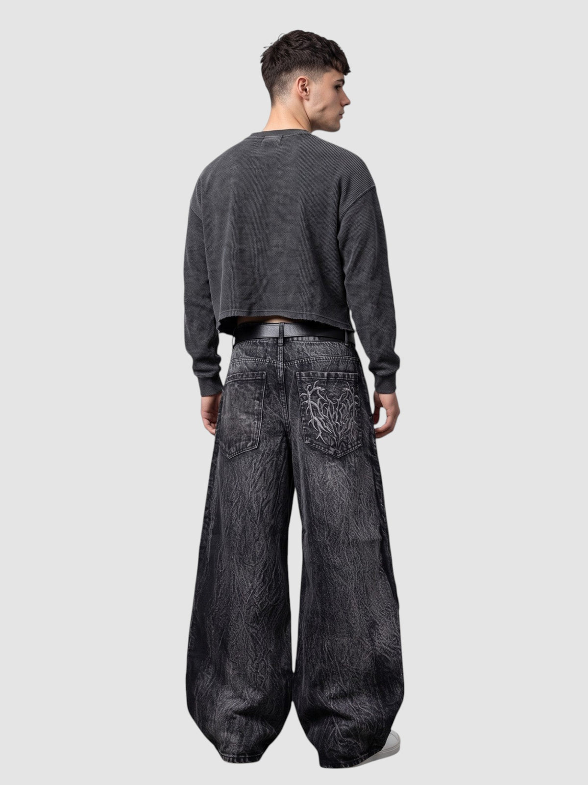Y2K Studio wide-leg acid wash black denim jeans with spiderweb embroidery on the back pockets and raw edge details.
